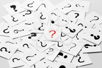 Pile of question mark signs scattered around with one red symbol in the center. Decision, enquiry or faq concept.