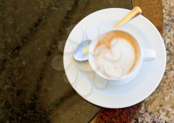 cup of cappuccino on stone table in outdoor cafe