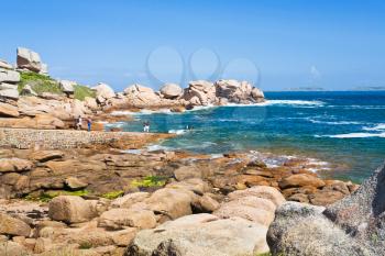tourists on Pink Granite Coast in Brittany in sunny day, France
