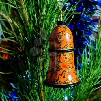 painted wooden bell and tinsel on Christmas-tree