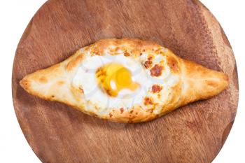 top view of Ajarian khachapuri (Georgian cheese pastry), filled with cheese and topped with a soft-boiled egg and butter on wooden board