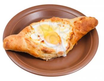 Ajarian khachapuri (Georgian cheese pastry), filled with cheese and topped with a soft-boiled egg and butter on ceramic plate isolated on white background