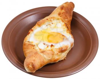 top view of hachapuri by Adzharia (Georgian cheese pastry), filled with cheese and topped with a soft-boiled egg and butter on ceramic plate isolated on white background