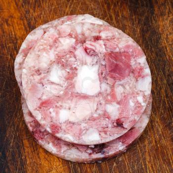 sliced head cheese on wooden cutting board