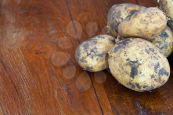 few yellow raw potatoes on wooden table
