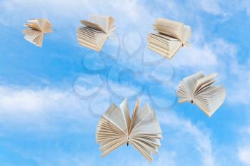 few book fly in blue sky with white clouds
