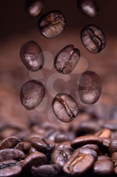 falling roasted coffee beans on black coffee background with focus foreground