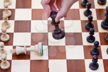 hand with Black King knocks white king on chess board
