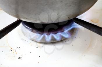 metal pan on burning gas in hearth ring of kitchen stove