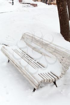 white snow-covered wooden bench on urban Bolotnaya Square, Moscow