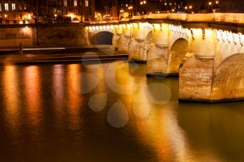 view of Pont Neuf through Seine river in Paris at night
