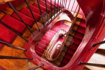 spiral steps with red carpet strip in old house in Paris