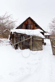 abandoned wooden barn in snow-covered village in winter day