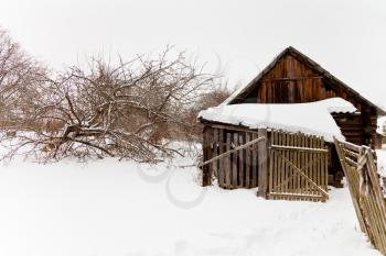 abandoned wooden shed in snow-covered village in winter day