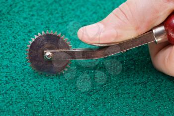 using of sewing tracing wheel on green textile