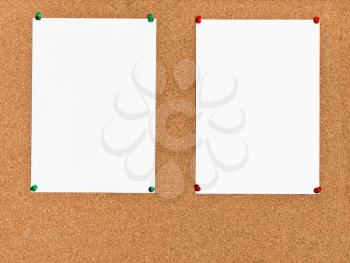 two white sheets of paper on cork board