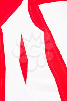 cutting out red woolen fabric along pattern lines for tailoring female dress