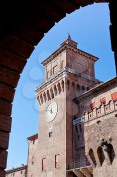 view on clock tower of castello estense from arch in Ferrara, Italy