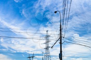 Electric power transmission under white cirrus clouds in blue summer
