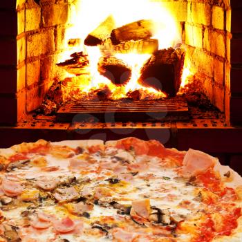italian pizza with ham and mushrooms and open fire in wood burning oven