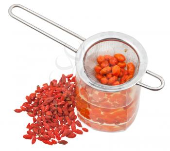preparing of goji berry tincture - strainer in glass with goji berries infusion and heap of dried fruits isolated on white background