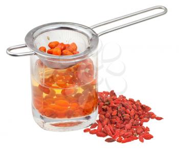 cooking of goji berry tincture - strainer in glass with goji berries infusion and handful of dried fruits isolated on white background