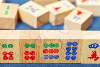 wood tiles closeup in mahjong game during playing on blue cloth table