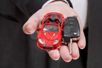 red car and key in businessman's hand close up