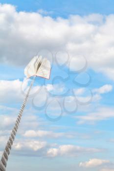 book tied on cord soars into light blue sky with white clouds