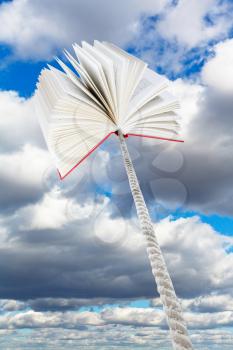book tied on rope soars into sky with grey clouds