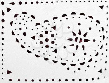 perforated paisley ornament on white leather close up