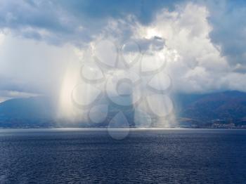 light of sun come through clouds near coastline of Calabria, Italy coastline inStrait of Messina