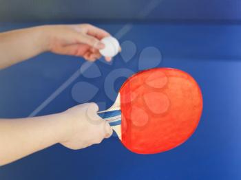 girl plays in table tennis with red racket on blue ping pong table close up