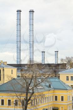 chimneys of district heating over urban houses in cold autumn day
