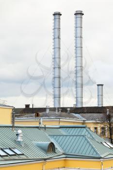 chimneys of district heating over urban roofs in cold autumn day