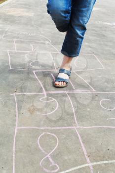 girl hops in hopscotch outdoors in sunny day