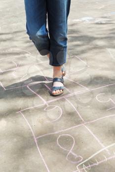 girl hopping in hopscotch outdoors in sunny day
