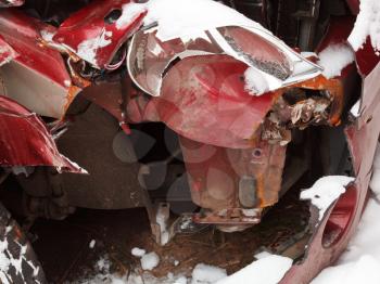 damaged headlight and crumpled hood of red car after winter traffic accident