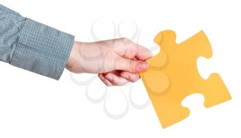 female hand holding big yellow paper puzzle piece isolated on white background