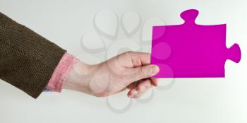 pink puzzle piece in male hand on grey background