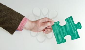 green painted puzzle piece in male hand on grey background