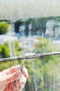 cleaning of home window glass by squeegee in sunny spring day