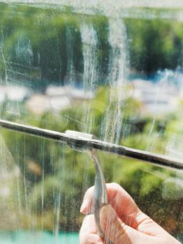 washing of home window glass by squeegee in sunny spring day