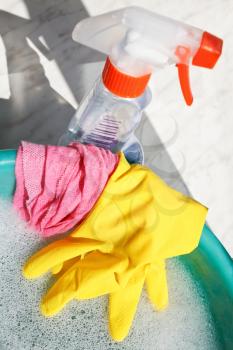 window washer set - rubber glove, wet duster, spray glass cleaner bottle, soap suds water in basin on windowsill