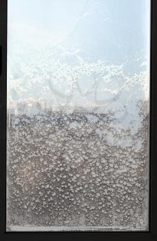 view of urban houses through frozen window in cold winter day