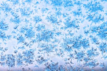 view of blue evening sky through snowflakes and frost pattern on window in cold winter