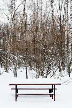 snow covered table on recreation ground of city park in winter