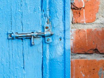 Espagnolette on old blue painted door of shed close up