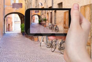 travel concept - tourist taking photo of old italian medieval street in historical center of Ferrara, Italy on mobile gadget