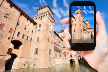 travel concept - tourist taking photo of moat and The Castle Estense in Ferrara on mobile gadget, Italy